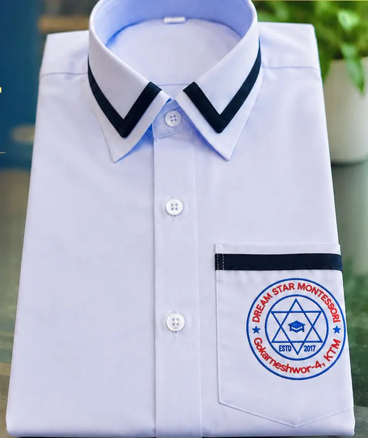 Folded white school shirt with navy-trimmed collar and pocket and a Dream Star Montessori badge